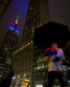 People walk in the rain past the Empire State Building as it is lit up in the colors of the South African flag in memoriam of Nelson Mandela s death