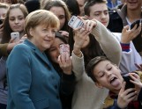 Pupils take mobile phone selfies with German Chancellor Angela Merkel