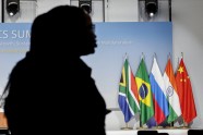 A woman stands near the flags of South Africa, Brazil, Russia, India and China during the 2023 BRICS Summit at the Sandton Convention Centre in Johannesburg on August 24, 2023